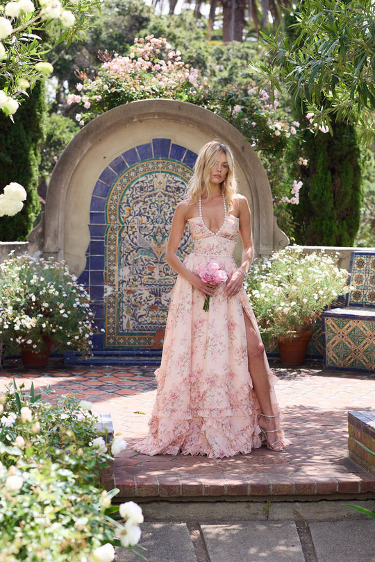 Graceful women's blush floral maxi gown with a V-neck and flowing ruffles, perfect for special occasions.