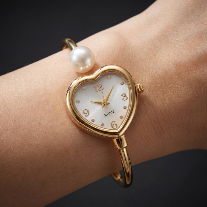 Elegant women's gold quartz watch with a delicate heart and pearl accent. Perfect jewelry bracelet watch.