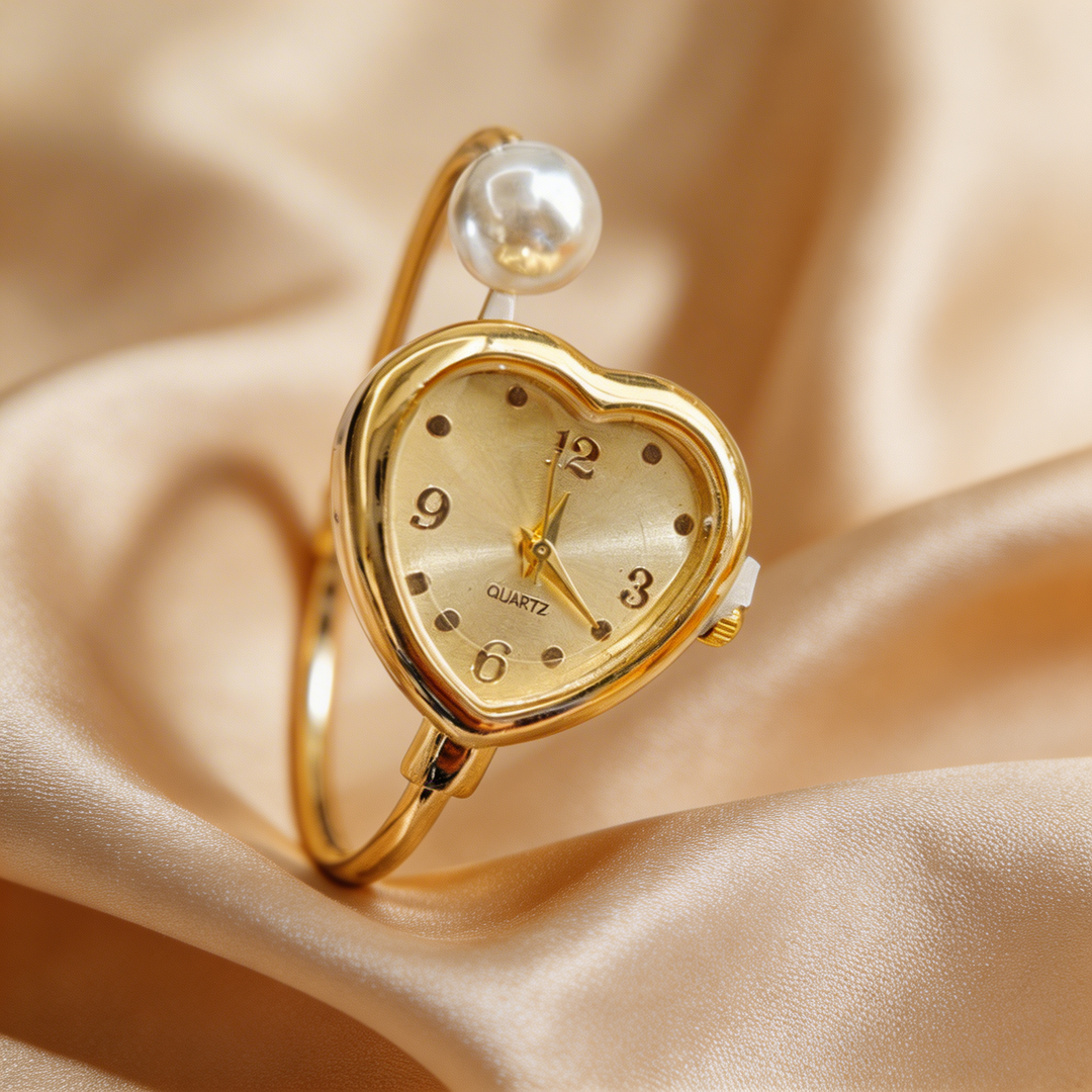 Close-up of elegant women's quartz watch, gold-toned with beautiful heart and pearl accents on the bracelet.