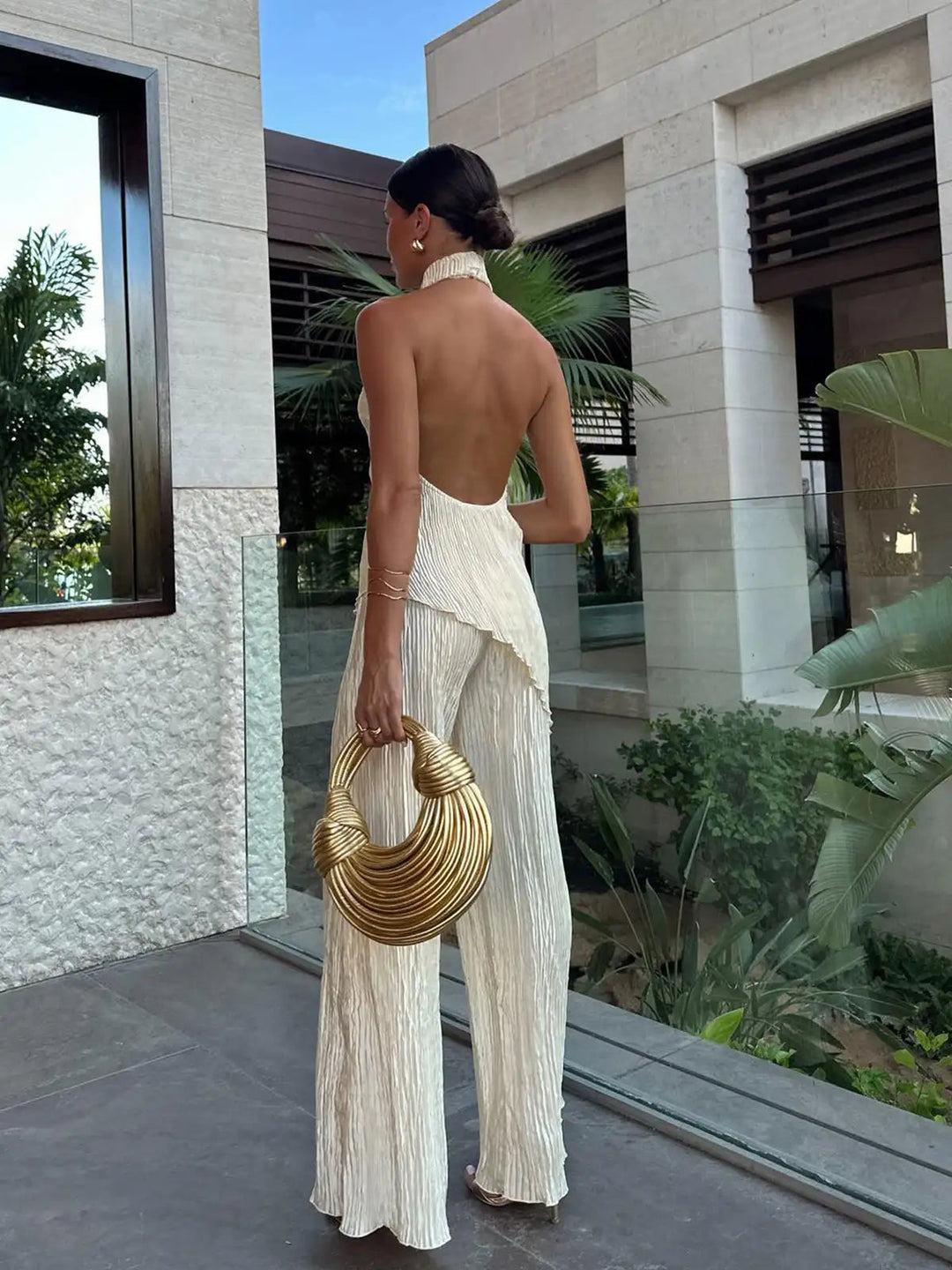 Chic women's pleated halter neck and wide-leg pants set. A versatile, elegant ensemble for formal events or parties.