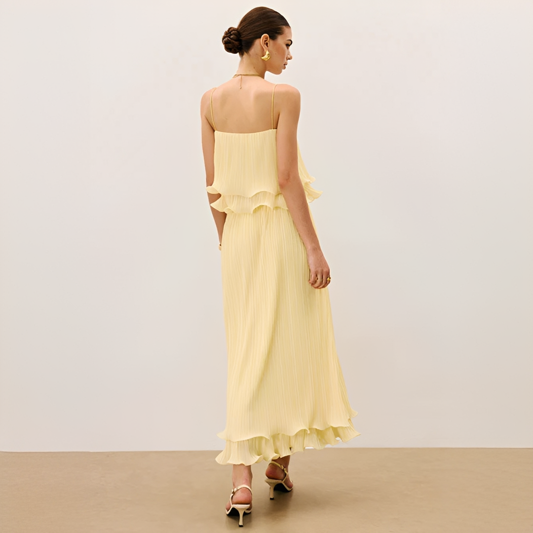 Woman models a chic pleated maxi co-ord set with ruffle detail. Elegant two-piece outfit, perfect for summer parties.