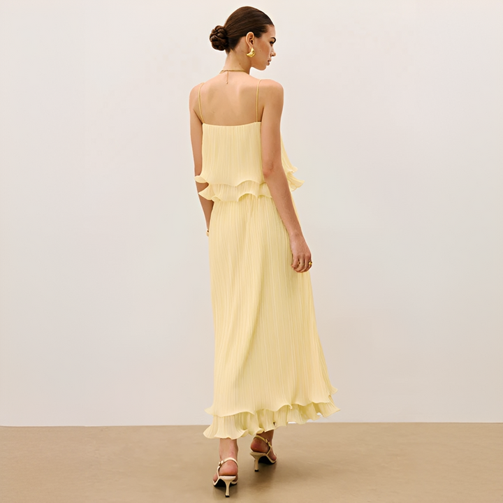 Woman models a chic pleated maxi co-ord set with ruffle detail. Elegant two-piece outfit, perfect for summer parties.