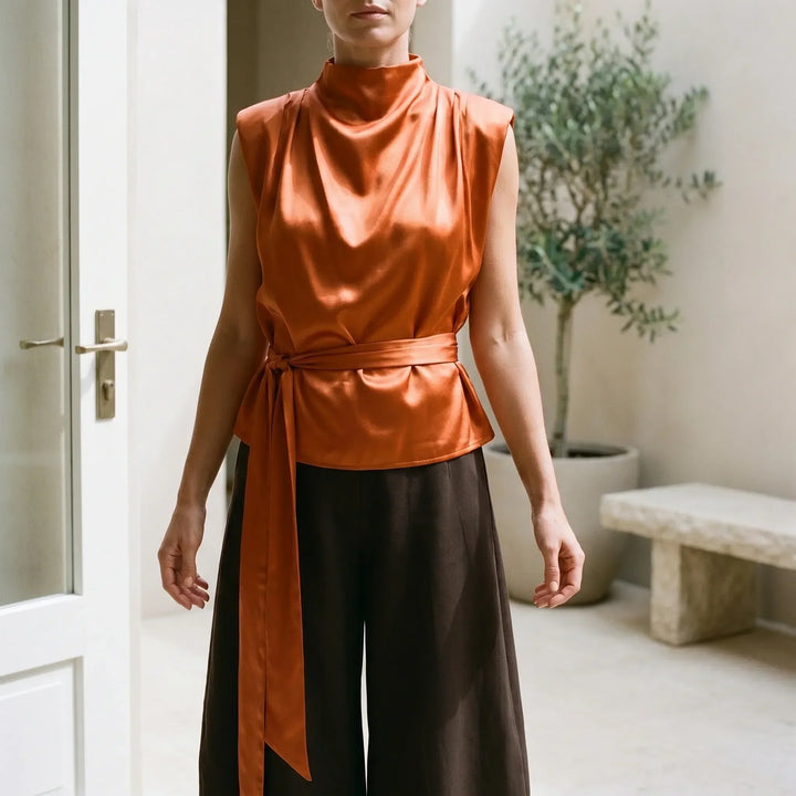Elegant women's sleeveless top featuring a chic tie-waist and graceful draped neckline. Perfect for evening wear.