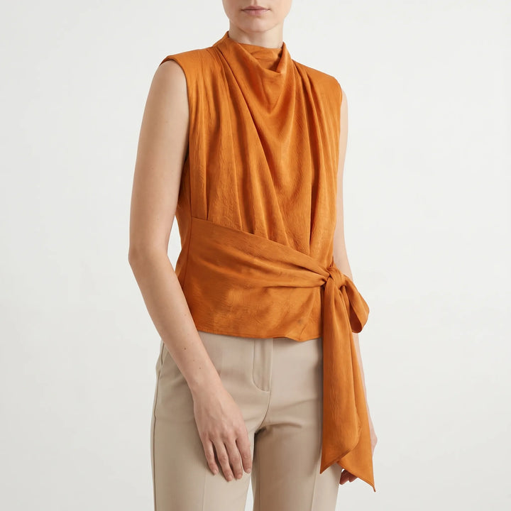 Chic textured sleeveless blouse with a stylish tie-waist and elegant draped neckline. Ideal for summer parties.