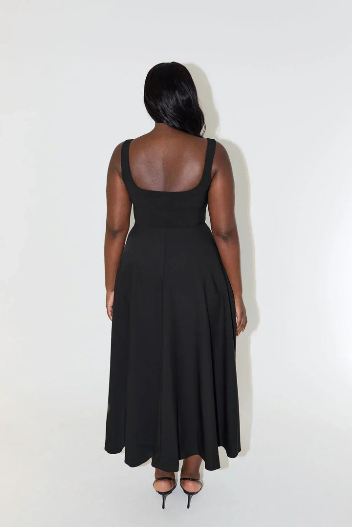 Side view of a woman wearing a flattering square neck midi dress, highlighting its elegant, timeless silhouette.