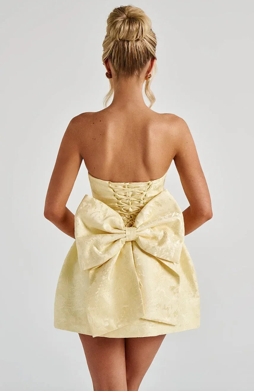 Yellow strapless mini dress for women, featuring a stylish bow back, ideal for cocktail parties.