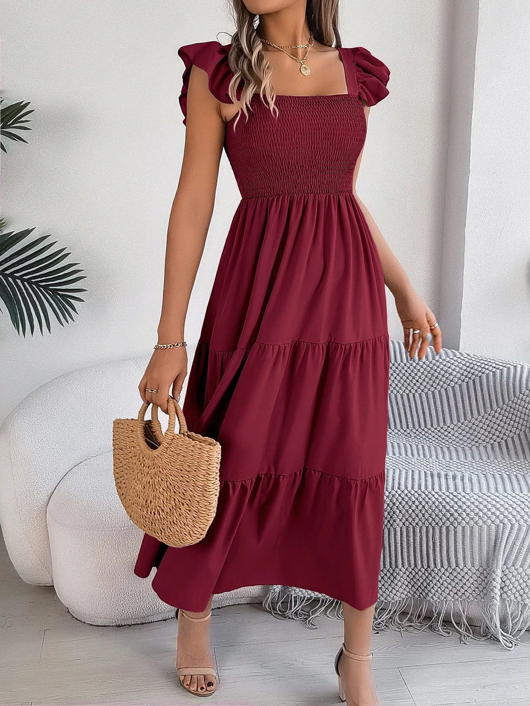 Women's smocked tiered midi dress with stylish ruffle sleeves, offering a comfortable and elegant summer look.