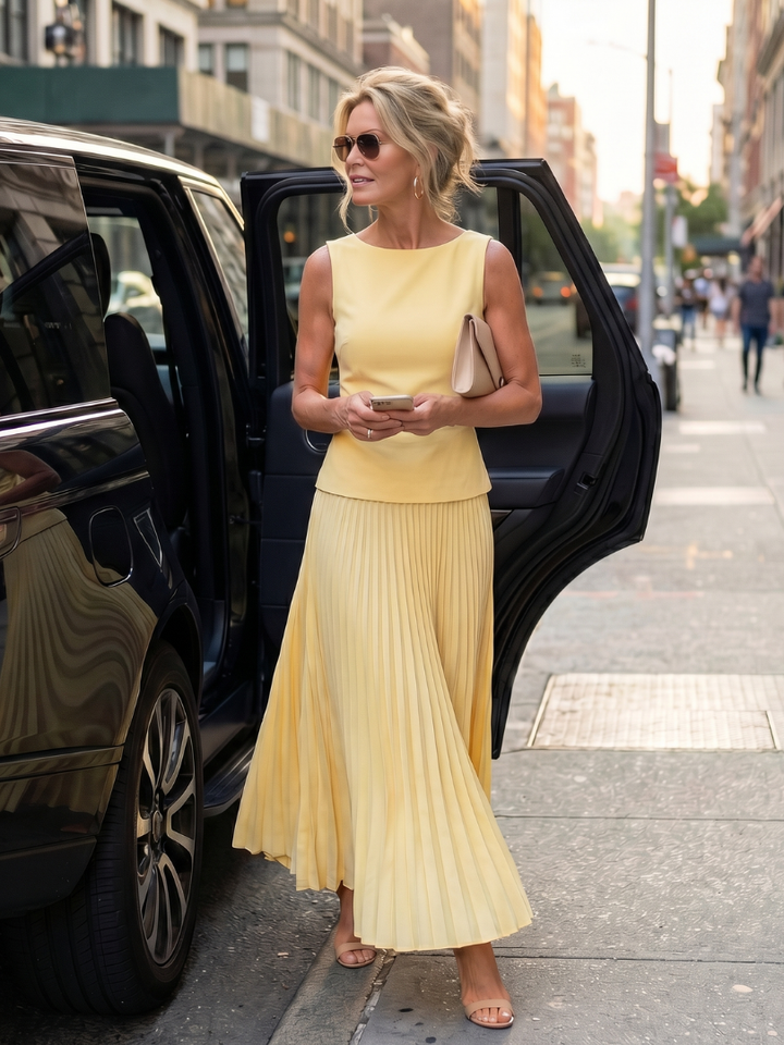 Side profile of a women's two piece pleated maxi skirt set, showing the structured bodice and skirt drape.