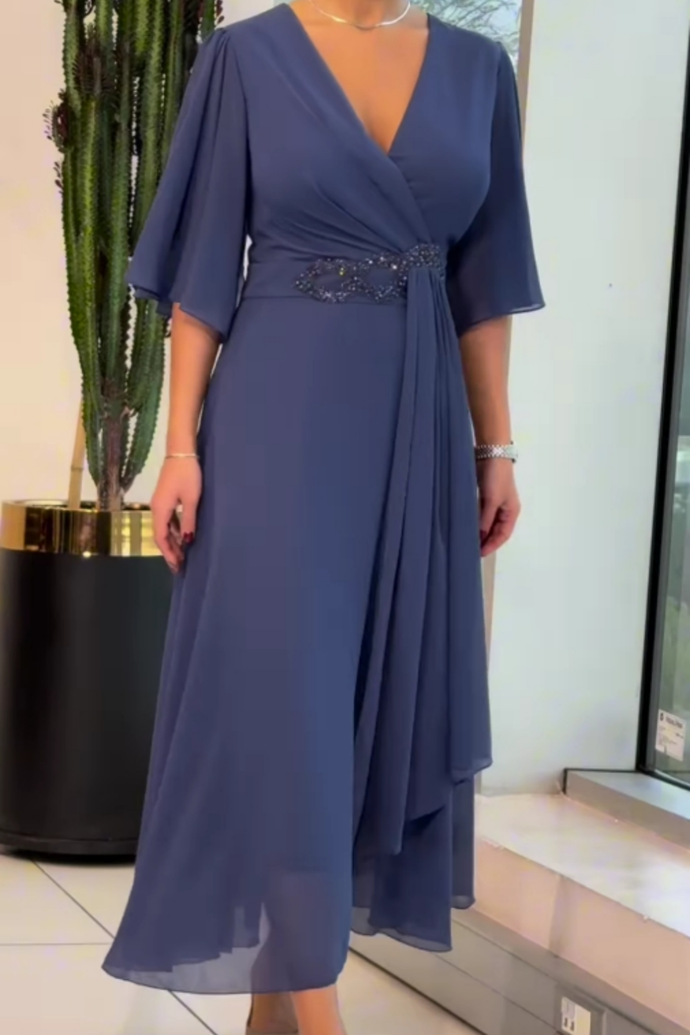 Woman in a versatile flowing V-neck maxi dress with adjustable straps, showcasing its comfortable and elegant design.