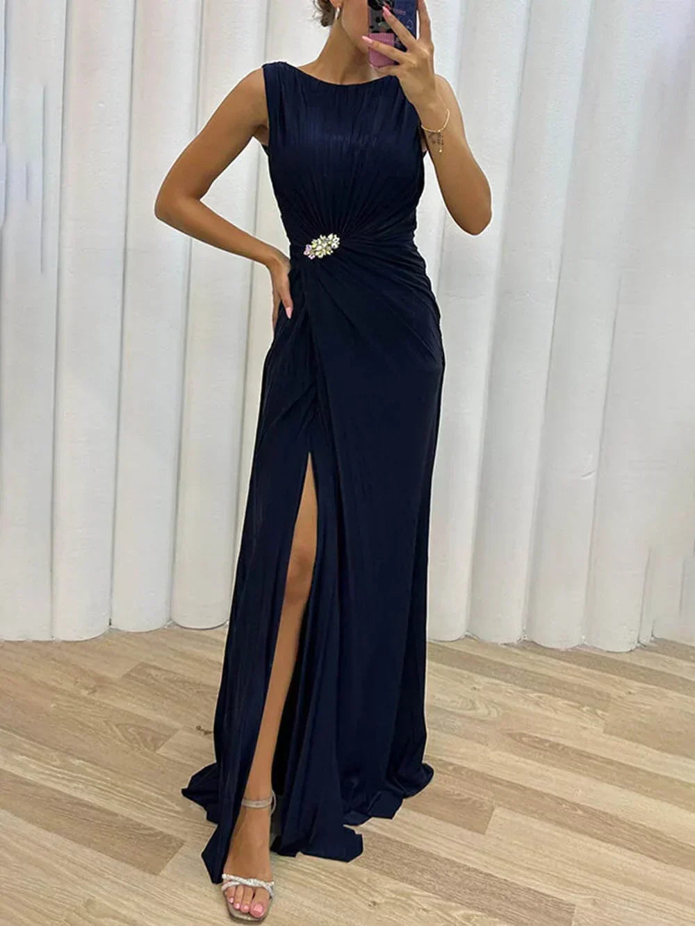 Glamorous navy blue draped maxi dress for wedding guests, featuring a high slit & elegant boat neckline.
