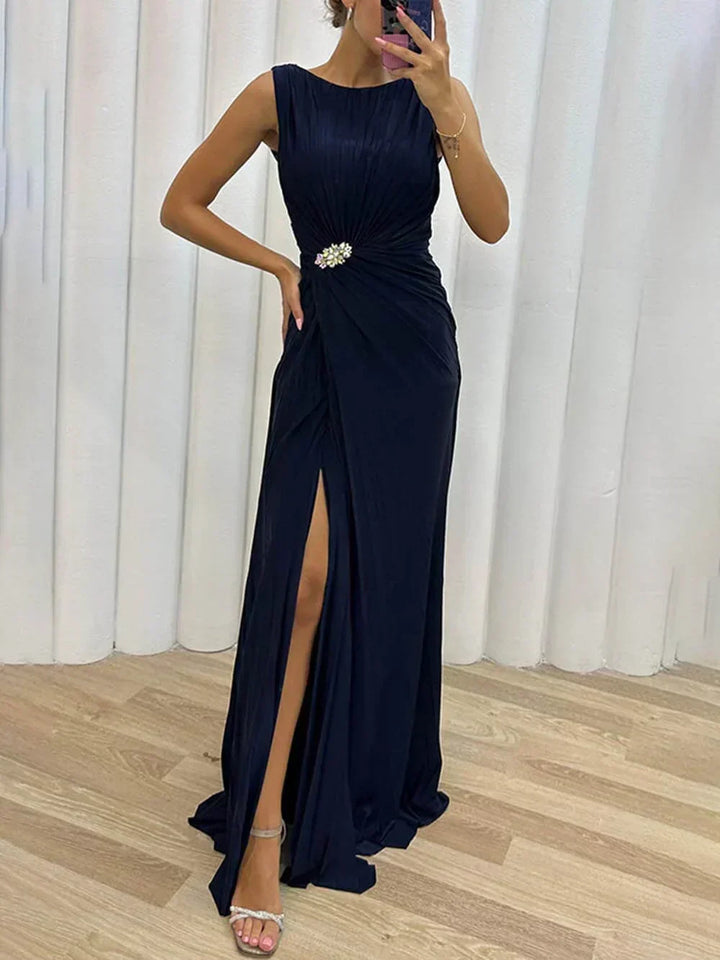 Glamorous navy blue draped maxi dress for wedding guests, featuring a high slit & elegant boat neckline.