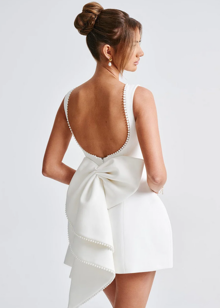 Elegant women's white mini dress with open back and delicate bow detail, perfect for parties & special occasions.