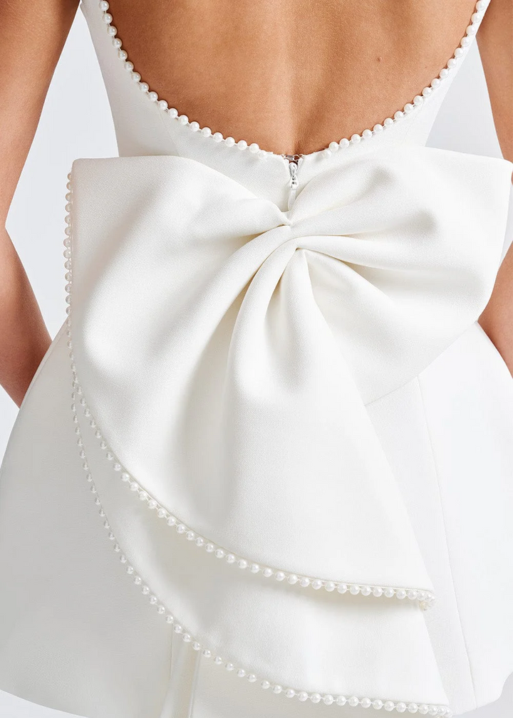 Form-fitting elegant women's mini dress with open back, adorned with a graceful bow. Ideal cocktail party wear.