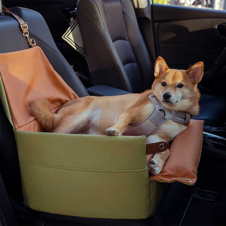 Small dog comfortably seated in an elevated faux leather car booster seat, black interior.