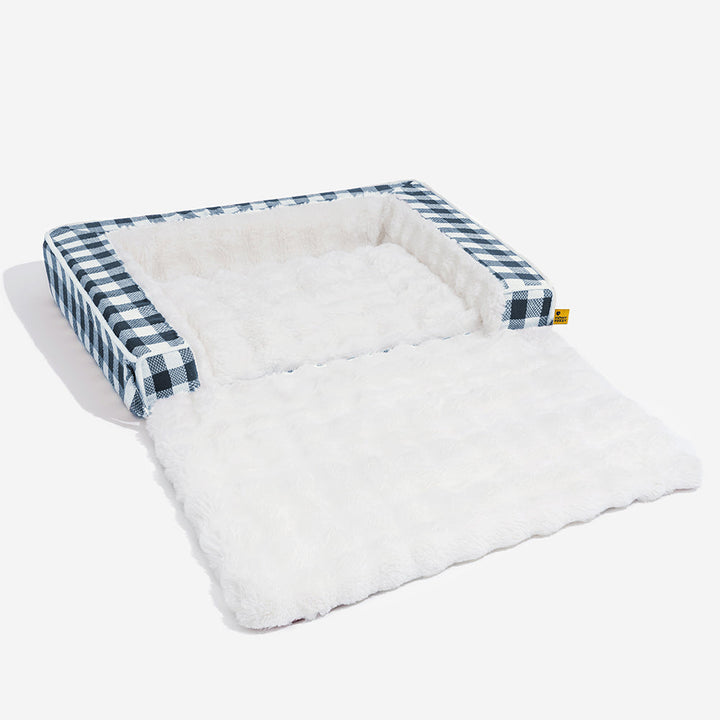 Calming ergonomic dog bed, gray plaid fabric, shown in a cozy home setting.