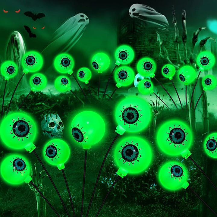 Four solar-powered scary eyeball Halloween lights illuminating a garden path