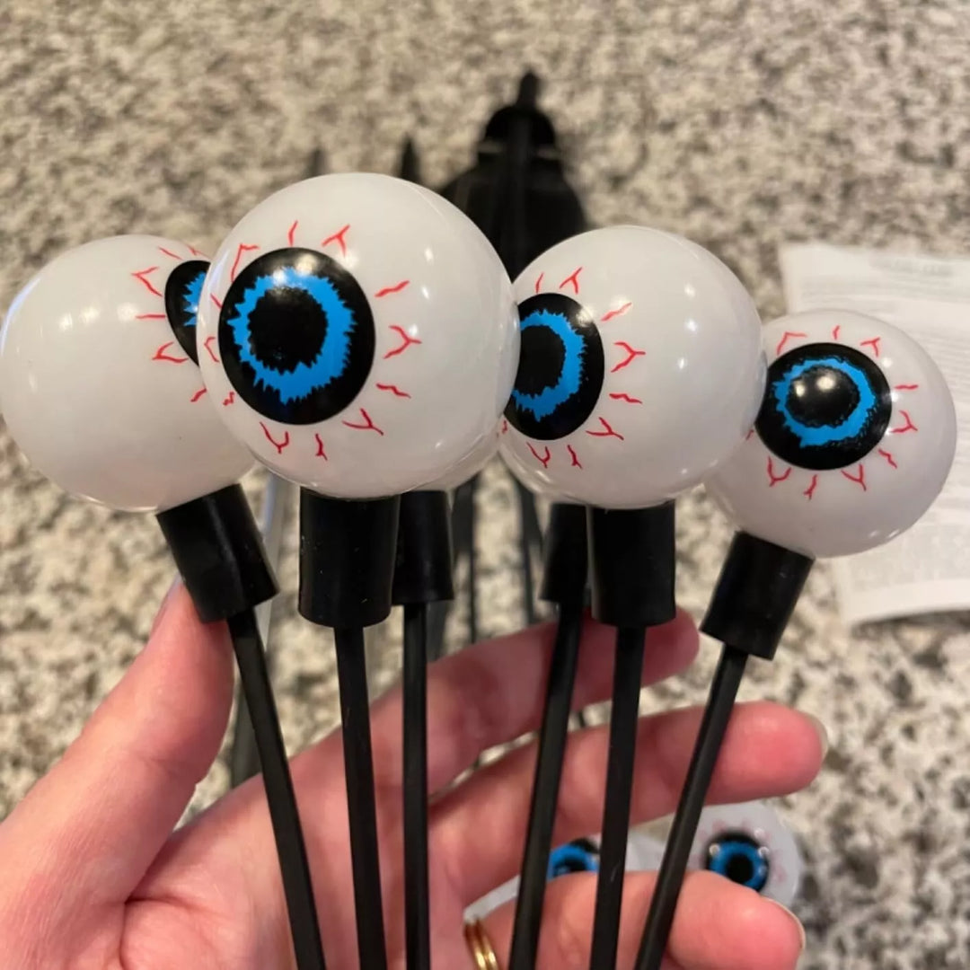 Decorative solar eyeball lights emitting a soft, spooky glow in a dark garden
