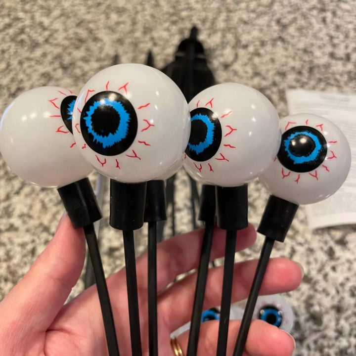 Decorative solar eyeball lights emitting a soft, spooky glow in a dark garden
