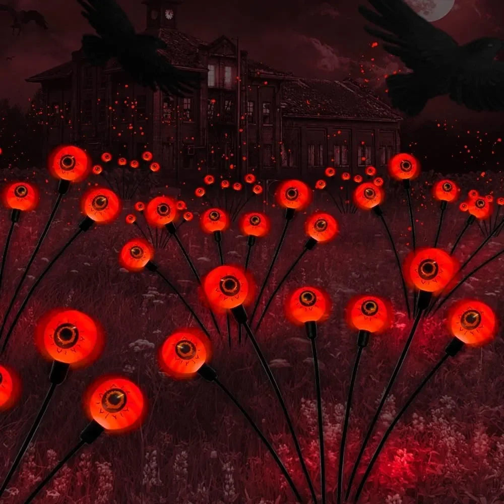 Four eyeball-shaped solar lights staked into a lawn, ready for Halloween night