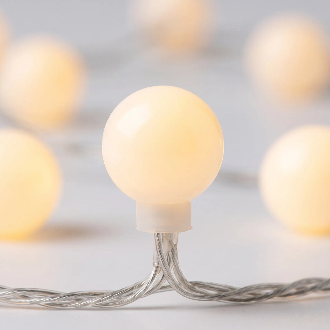 Warm white frosted globe LED string lights, great for creating cozy bedroom mood lighting or patio decor.
