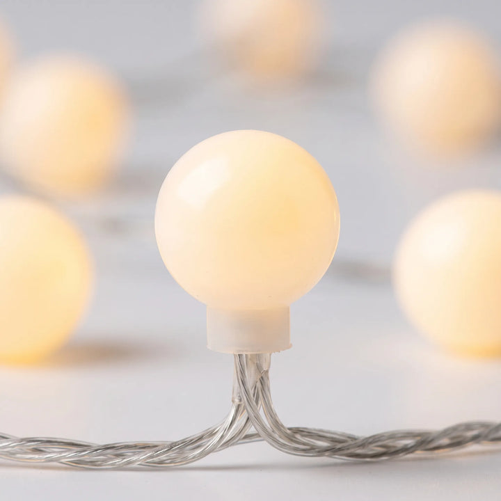 Warm white frosted globe LED string lights, great for creating cozy bedroom mood lighting or patio decor.
