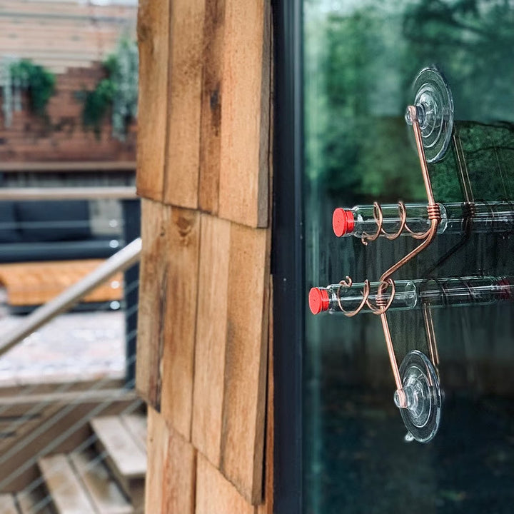 Copper and aluminum geometric window feeder, perfect for bird watching and modern outdoor spaces.