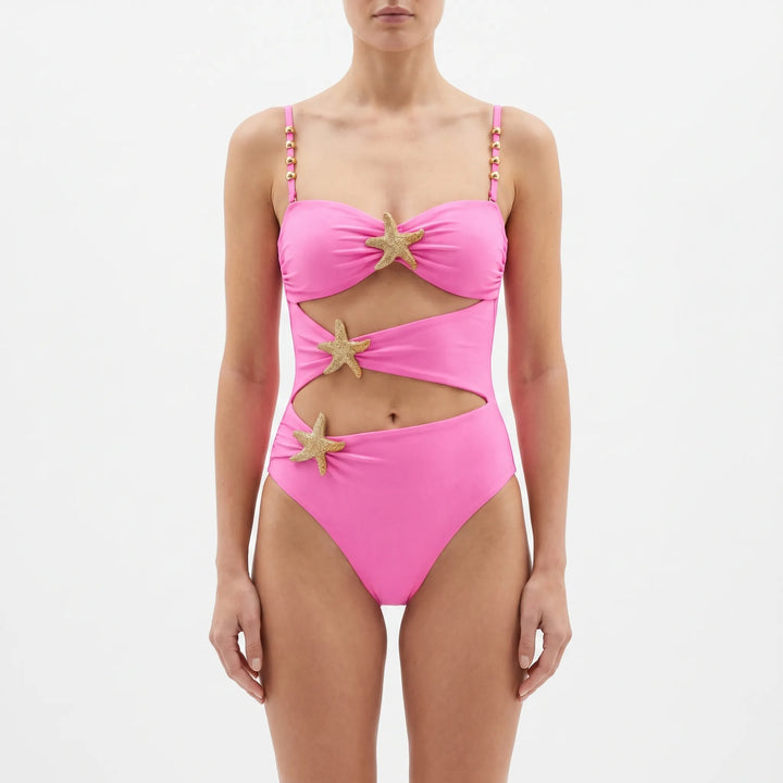 Confident woman modeling a glamorous cutout one-piece swimsuit by the pool.