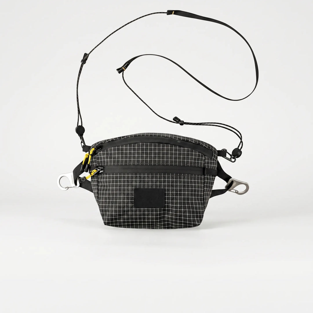 Person wearing gray cross chest bag with grid pattern, a compact & organized sling for daily essentials & travel.