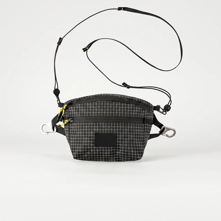 Person wearing gray cross chest bag with grid pattern, a compact & organized sling for daily essentials & travel.