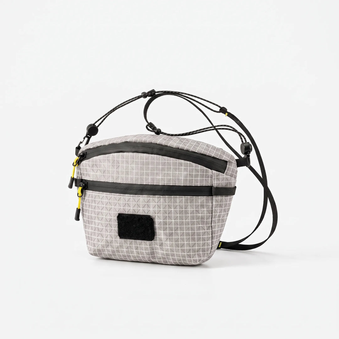 Close-up of gray cross chest bag with distinctive grid pattern fabric, highlighting its durable and stylish design for travel.