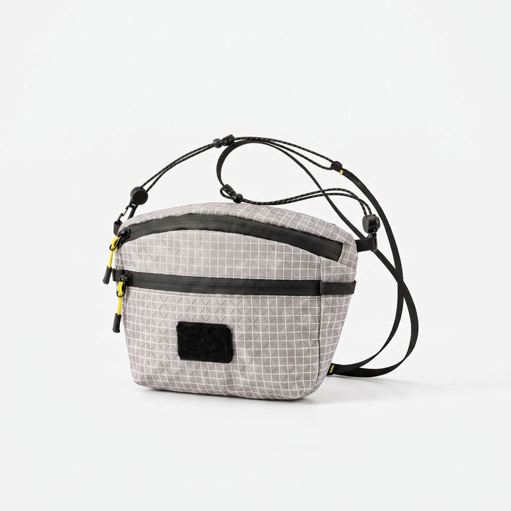 Close-up of gray cross chest bag with distinctive grid pattern fabric, highlighting its durable and stylish design for travel.