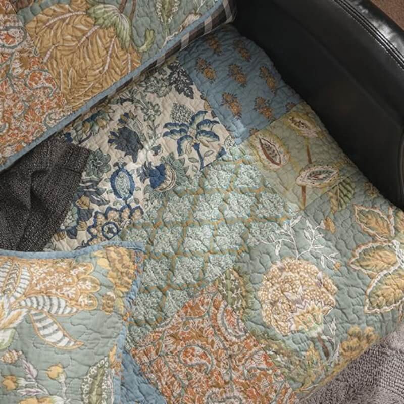 Green floral sofa protector draped over a couch, showing quilted texture and non-slip backing.