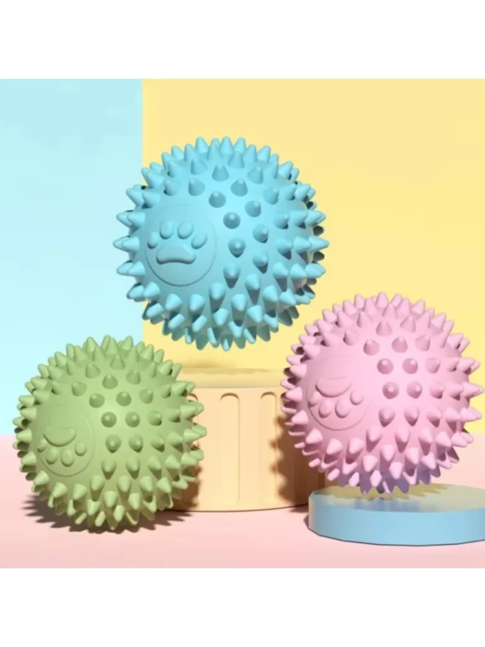 Puppy happily playing with a green rubber dental chew ball, an interactive pet care toy.