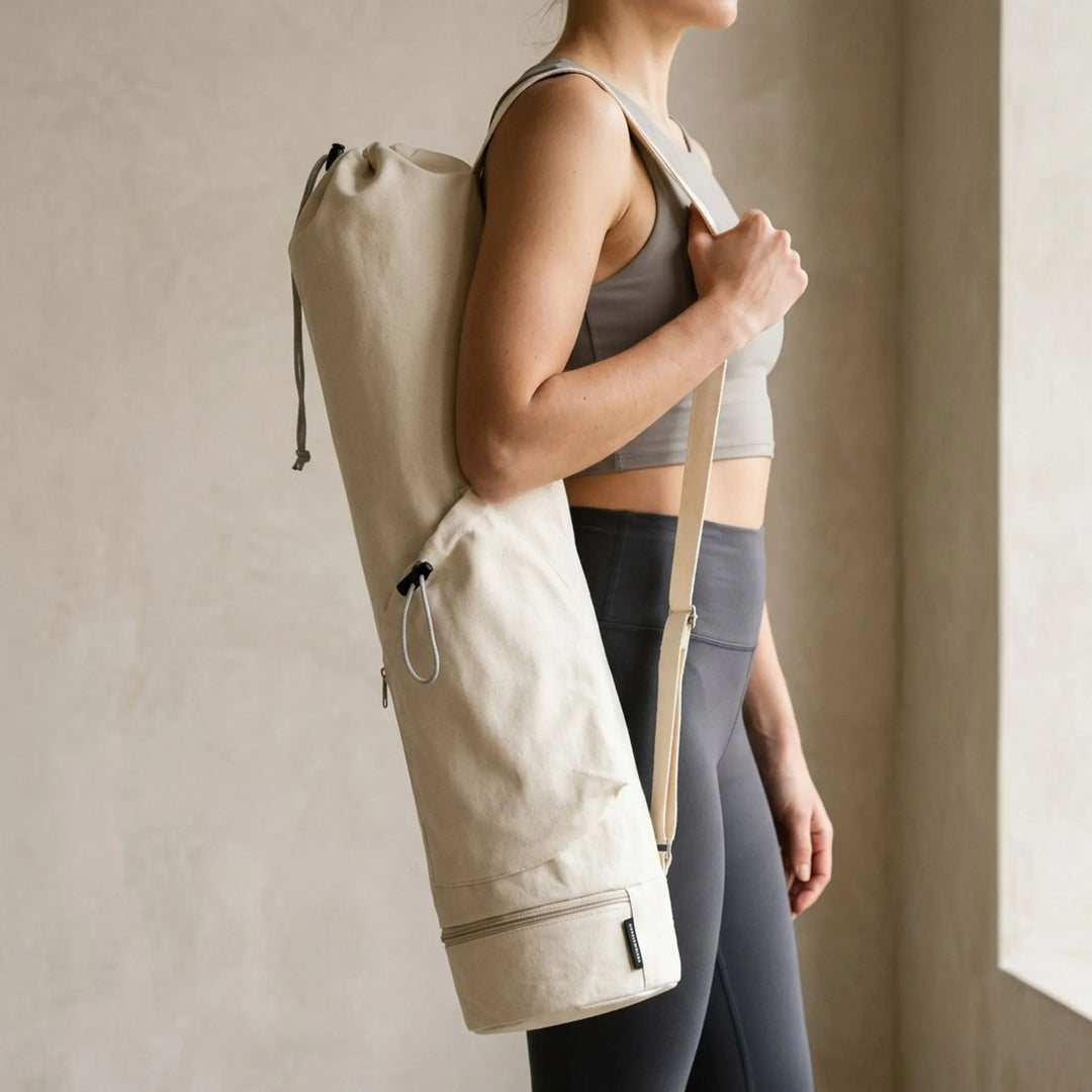 Green women's cylindrical yoga mat carrier bag for fitness, hands-free transport to gym or studio.