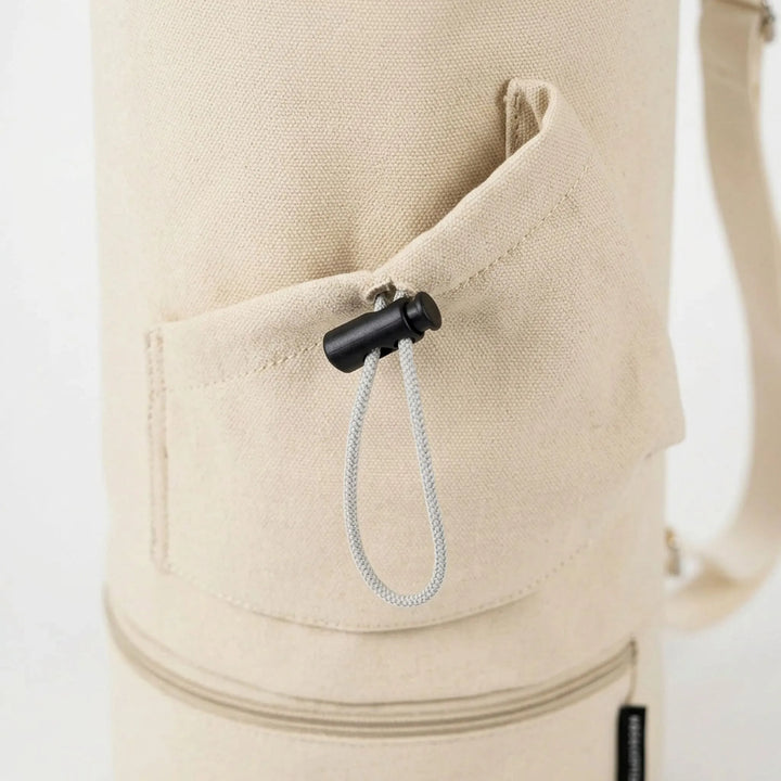 Beige cylindrical yoga mat carrier, a convenient gym bag for women's fitness and hands-free travel.
