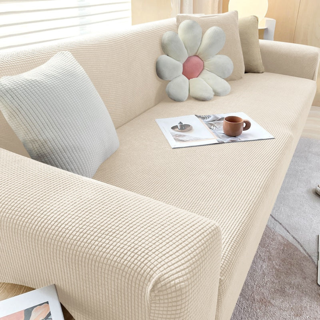 Grey elastic sofa slipcover protecting a three-seater couch in a modern living room setting