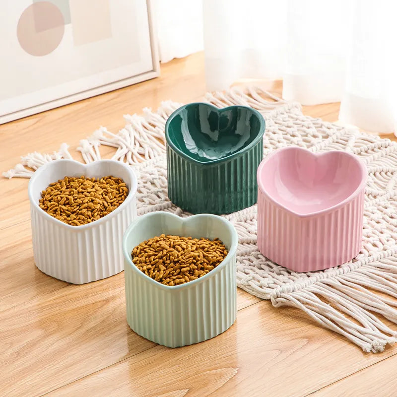 Closeup of red heart-shaped ceramic pet food bowl, non-slip base for hygienic feeding.