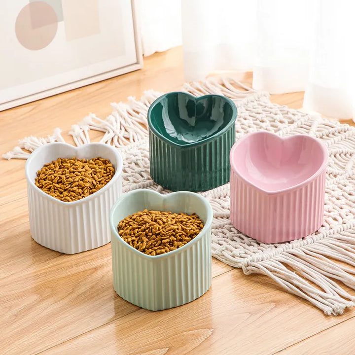 Closeup of red heart-shaped ceramic pet food bowl, non-slip base for hygienic feeding.