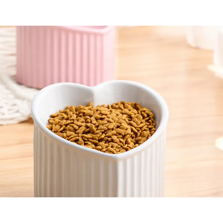 Set of two heart-shaped ceramic pet bowls, red and white, non-slip feeders for food and water.