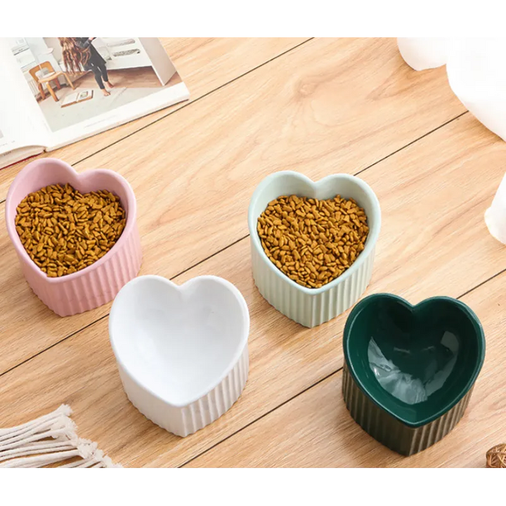 Heart-shaped ceramic pet bowl on a wooden floor, showcasing its non-slip design and hygiene.