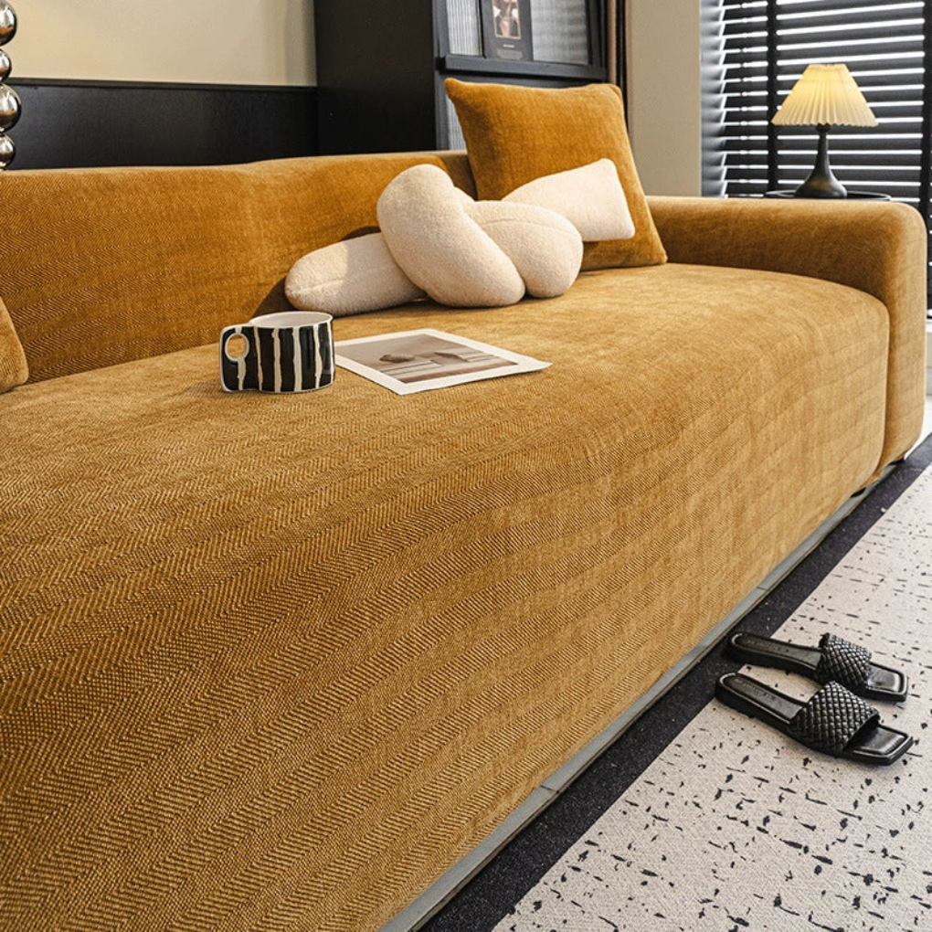 Elastic herringbone sofa cover snugly fitted on a three-seater couch, showcasing its stretch fit design and durability.