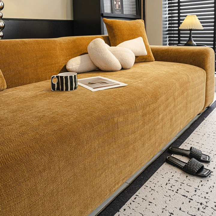 Elastic herringbone sofa cover snugly fitted on a three-seater couch, showcasing its stretch fit design and durability.