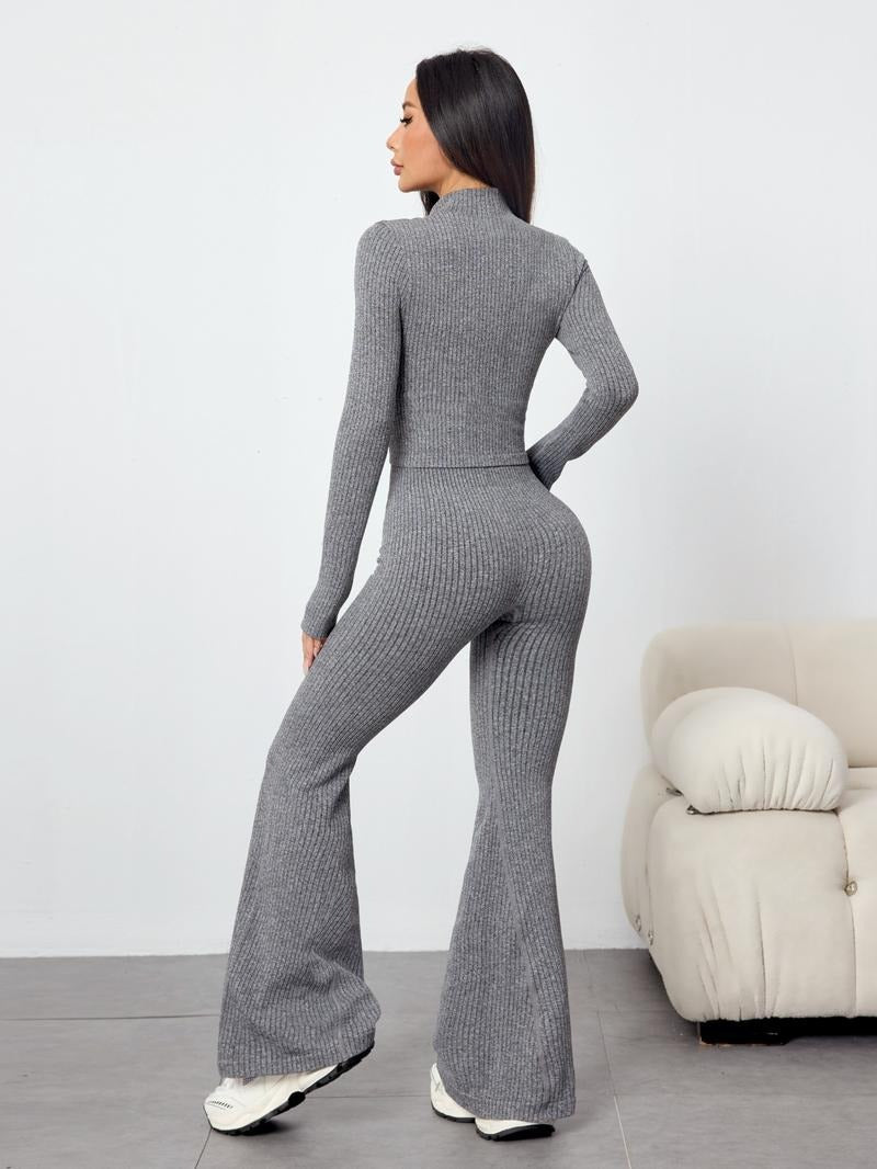 Woman in a chic ribbed knit two-piece set, long sleeve top & flare pants, perfect for versatile wear.
