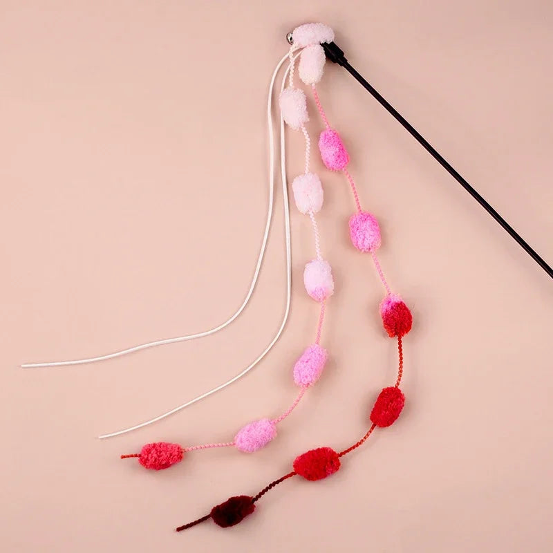 Dynamic shot of a cat playfully pouncing on an interactive teaser wand with a bell and tassel toy