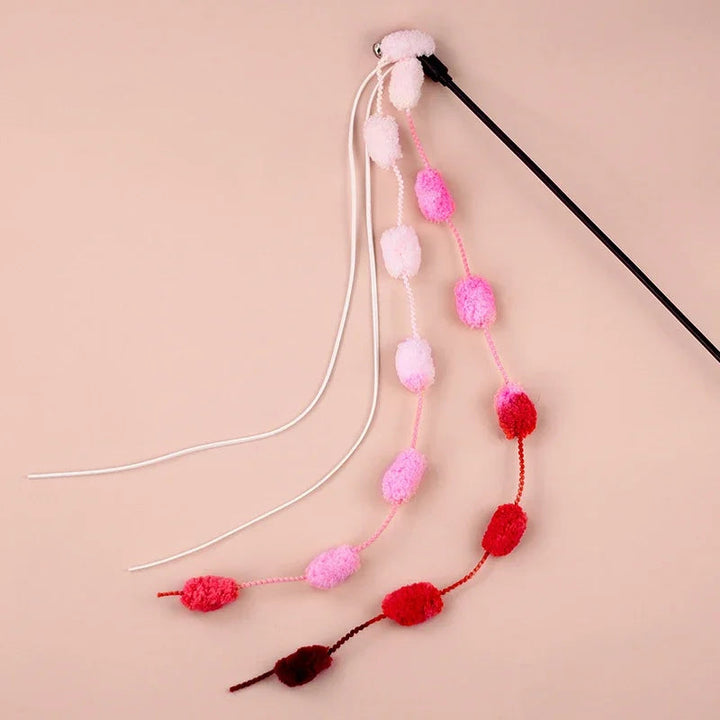 Dynamic shot of a cat playfully pouncing on an interactive teaser wand with a bell and tassel toy