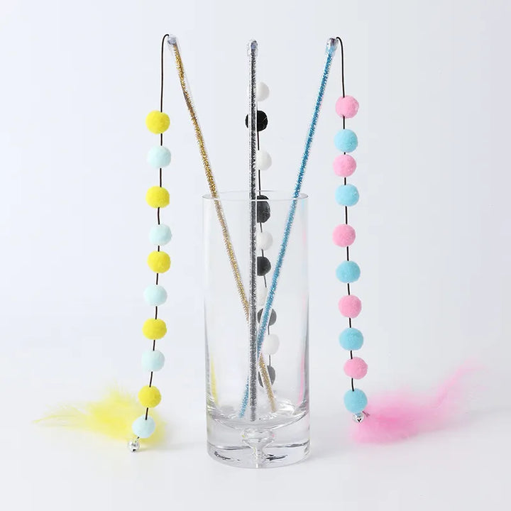 Close-up of interactive cat wand toy's fluffy pompoms and delicate feathers, enticing for feline fun.