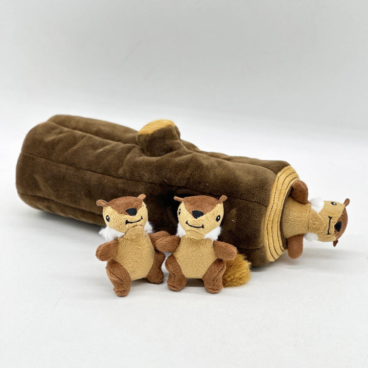 A happy dog engaging with an interactive brown tree trunk puzzle toy with squeaky squirrels