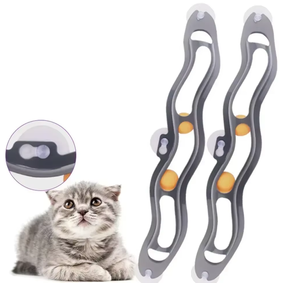 Close-up of a cat batting at a ball within an interactive window track toy securely attached by suction cups.