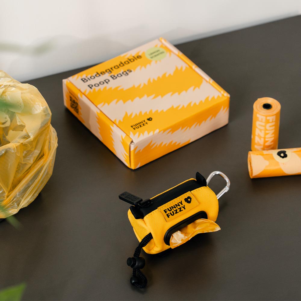 Hand holding a lemon scented biodegradable poop bag, demonstrating ease of use