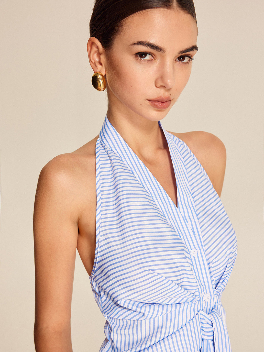 Elegant sleeveless light blue striped halter blouse with stylish tie-front detail. Ideal for work or casual.